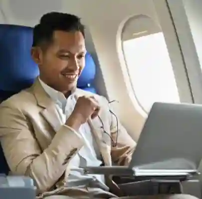 an individual running laptop on a plance by putting his laptop on lap 